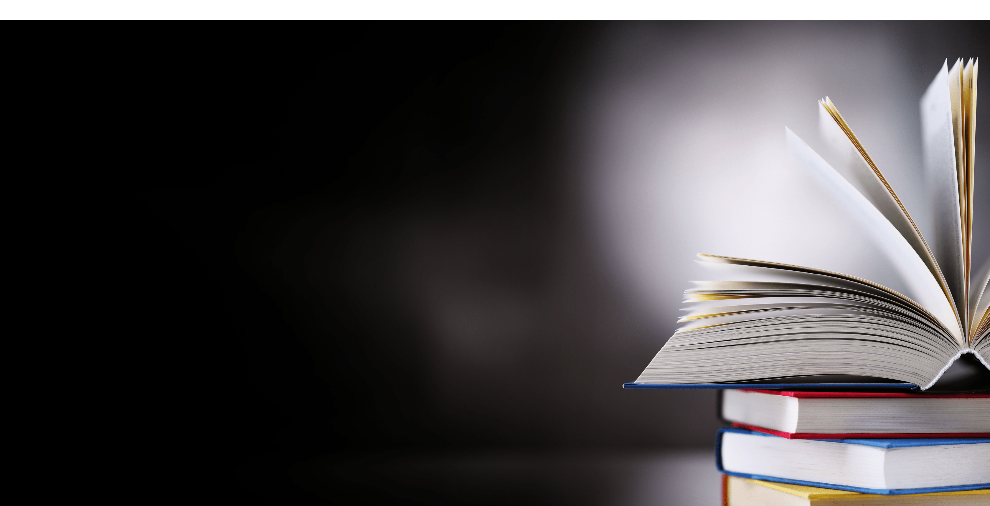 A composition with an open hardcover book lying on a stack of other books 