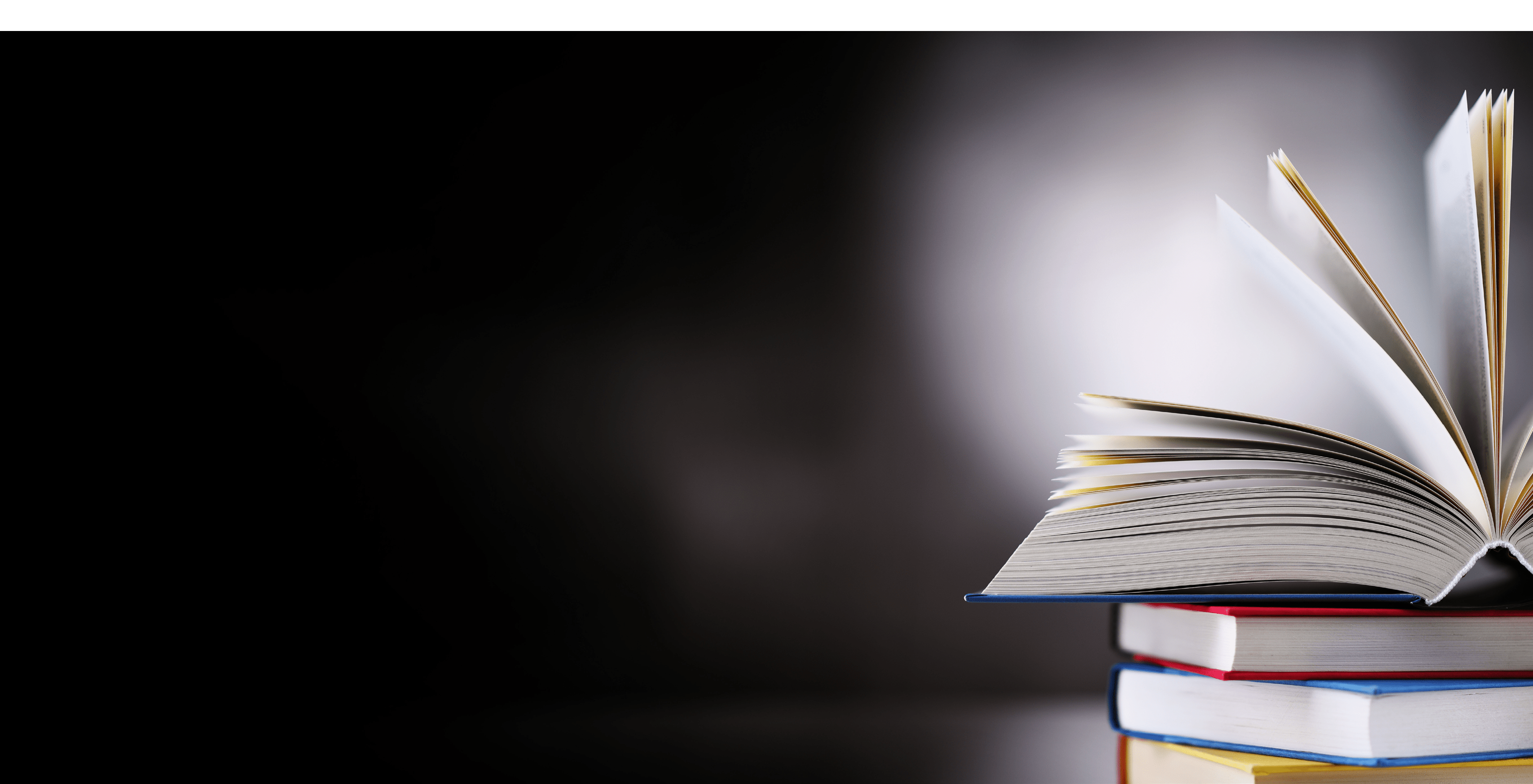 A composition with an open hardcover book lying on a stack of other books 